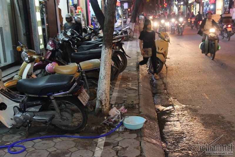 Phần dành cho người đi bộ bị gốc cây chắn lối. Dưới gốc lại có cả chậu nước, rác thải. Ảnh: Vietnamnet